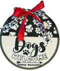 Round sign with paw print pattern, red ribbon, and 'Dogs Welcome People Tolerated' text on a white background.