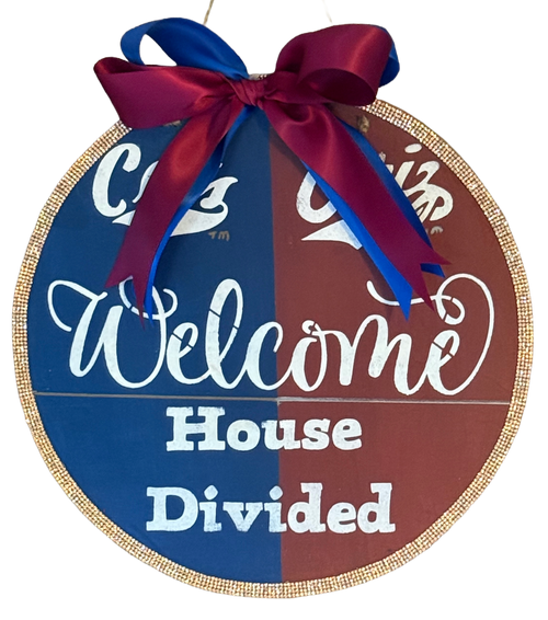 Round decorative sign with 'Welcome House Divided' text and a bow on a white background
