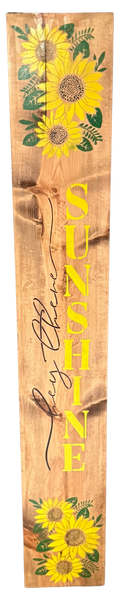 Wooden sign with sunflower designs and the word 'SUNSHINE' on a wooden background
