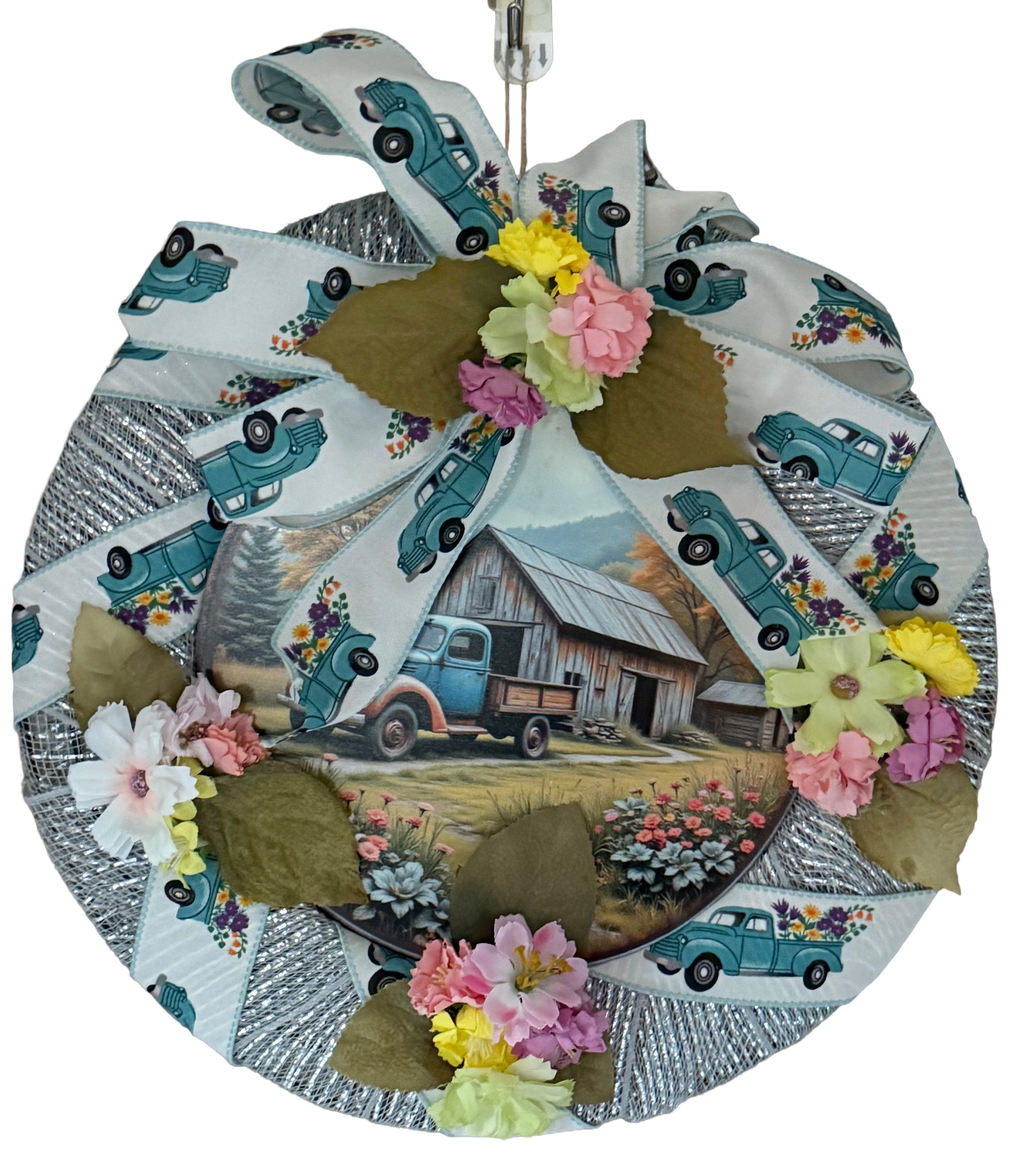 Round wreath with vintage truck and barn design, featuring flowers on a white background.