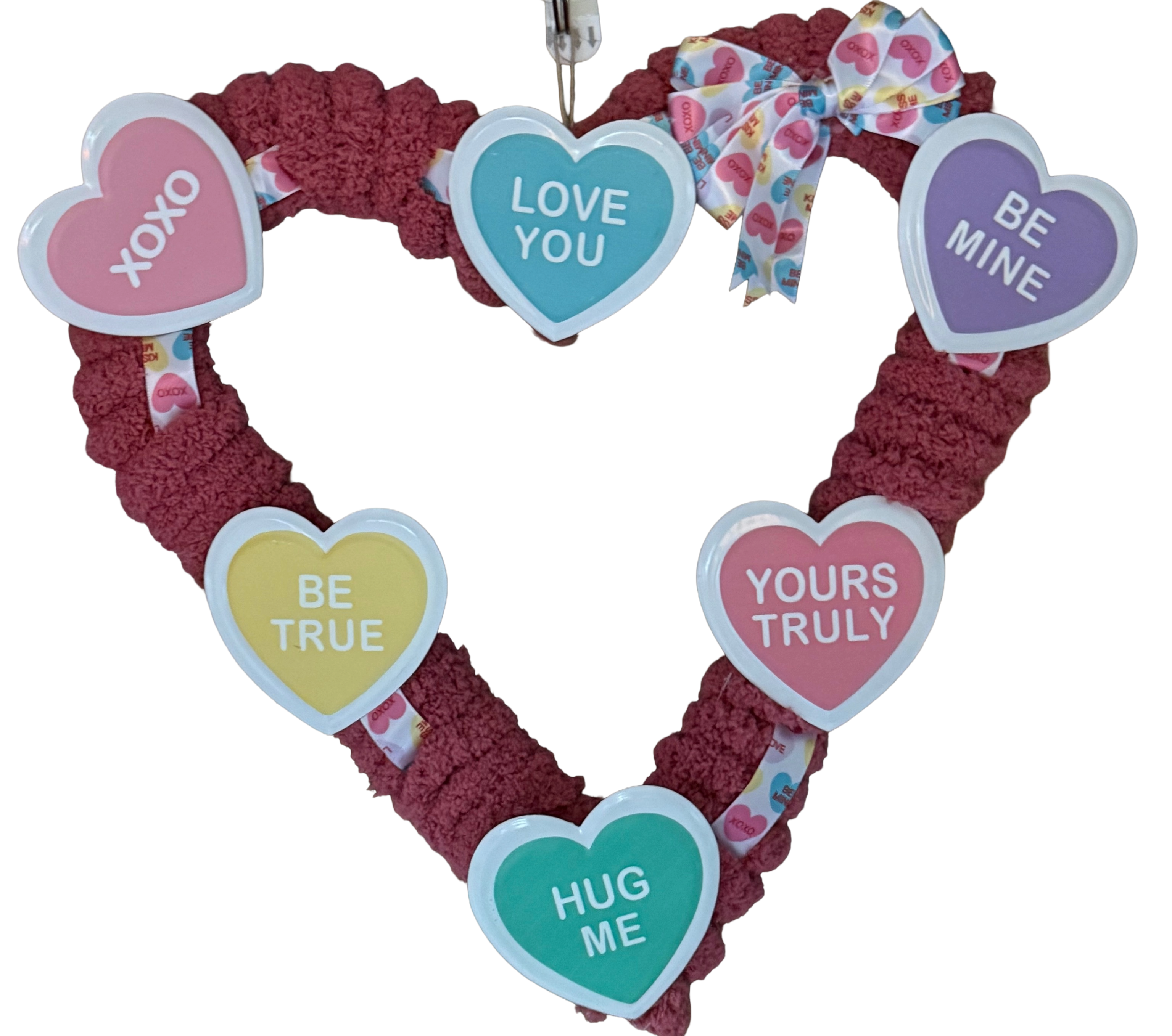 Heart-shaped wreath with colorful conversation hearts on a white background.