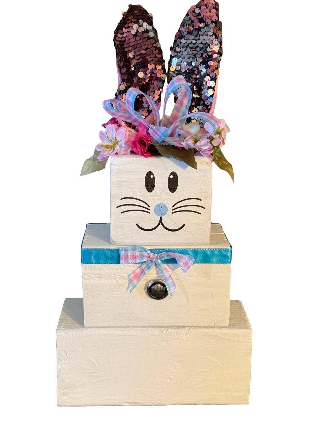 Stack of wooden blocks with bunny face, sequin ears, and colorful bow on a white background