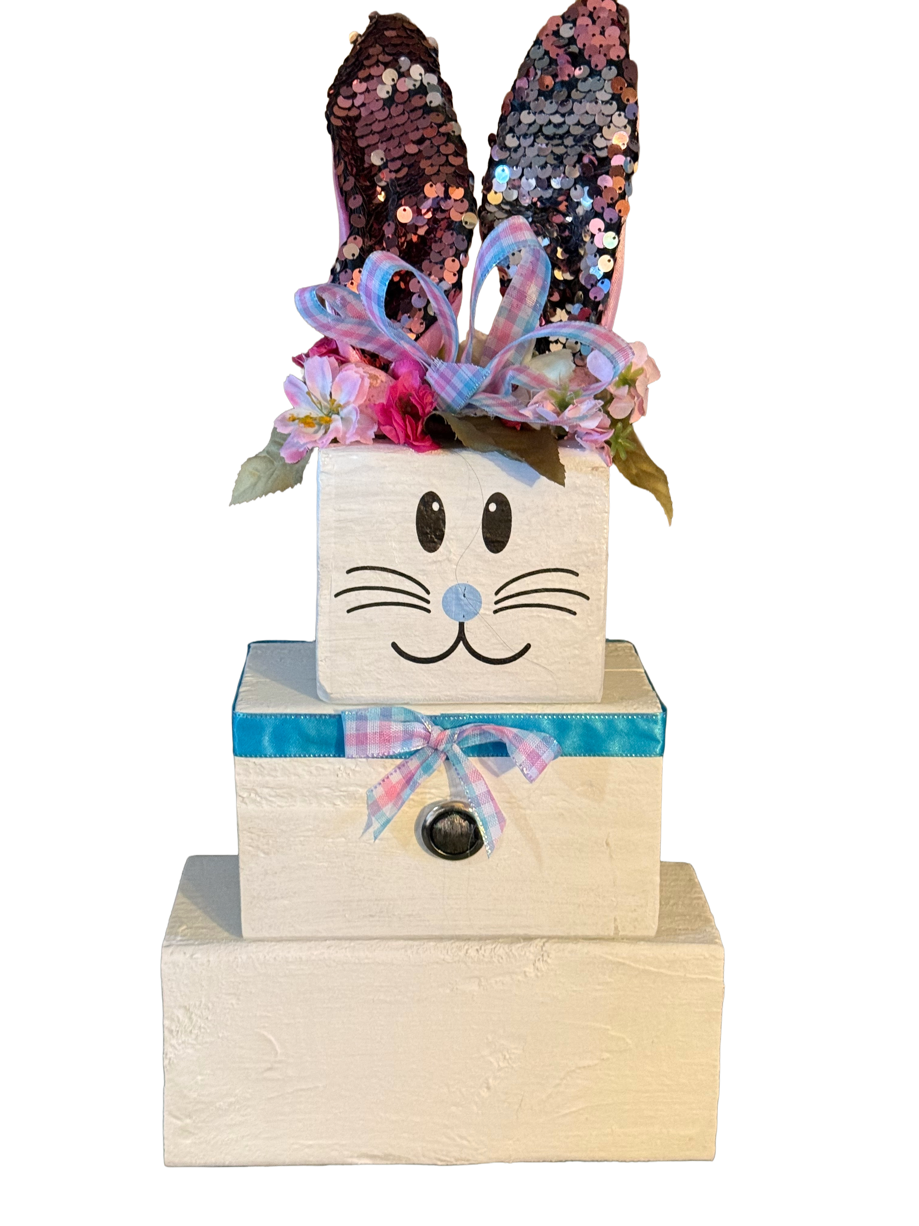 Stack of wooden blocks with bunny face, sequin ears, and colorful bow on a white background