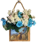 Decorative wall hanging with blue and white flowers and a scenic background.