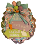 Decorative Easter wreath with colorful ribbons, eggs, and bunny elements on a white background.